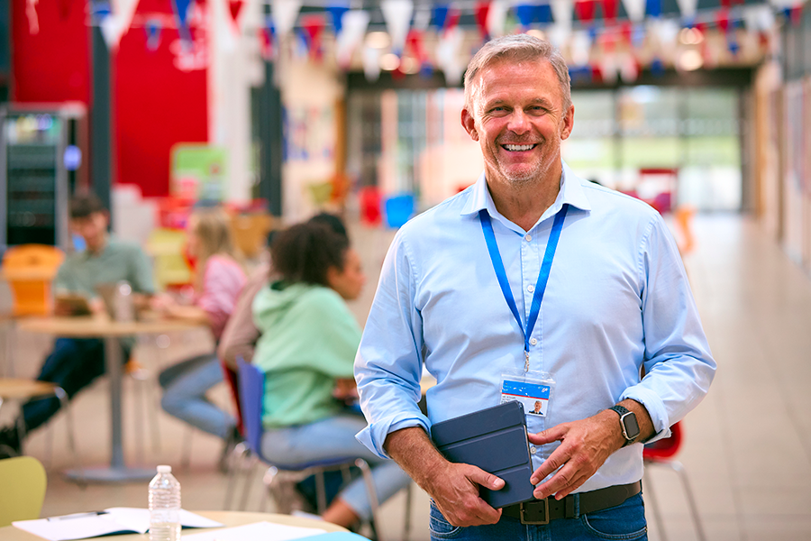 Man in school cafeteria with students in background